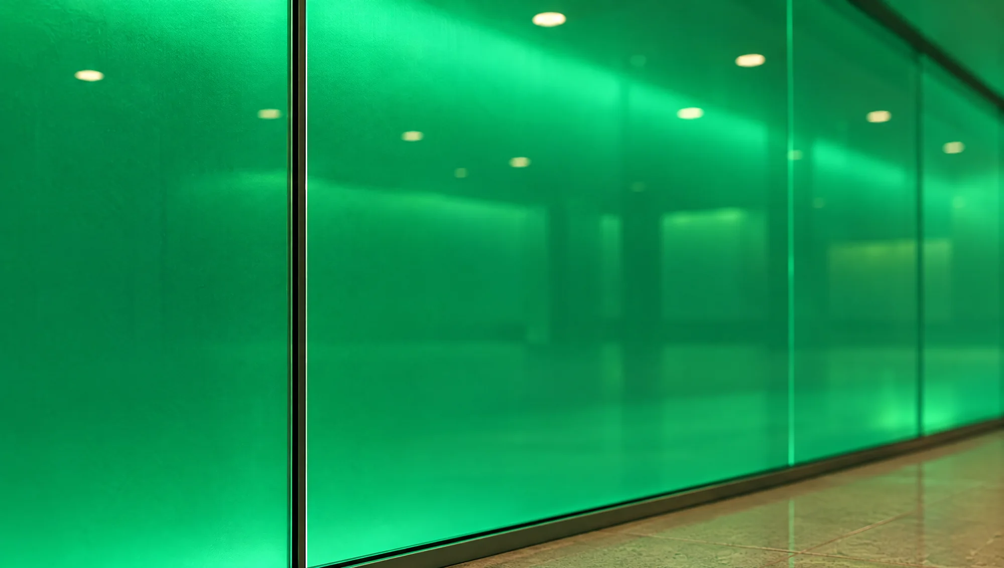 Detail of the backlit green glass wall panels with ceiling lights reflected