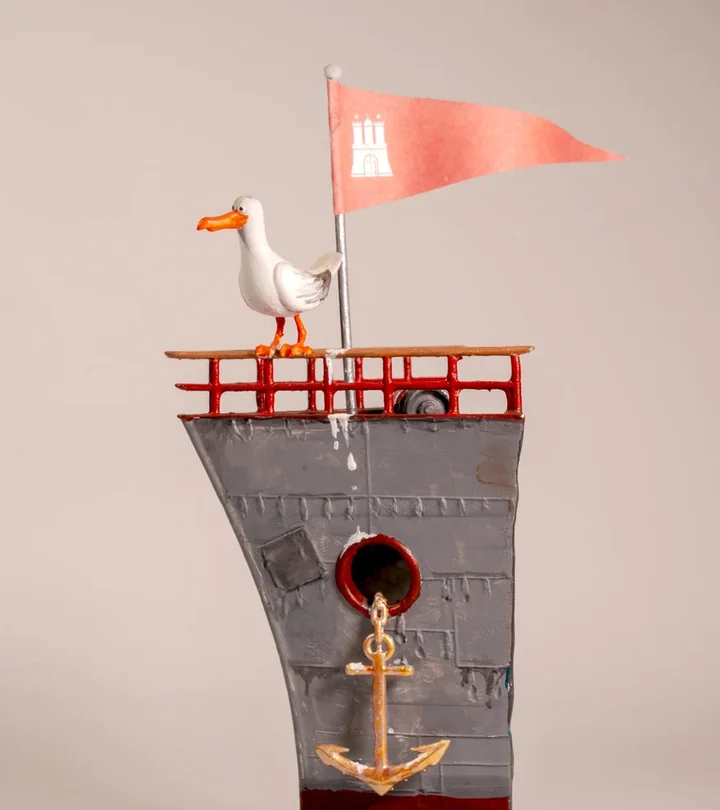 A painted model seagull with a Hamburg pennant standing on the crow's nest of a ship's bow