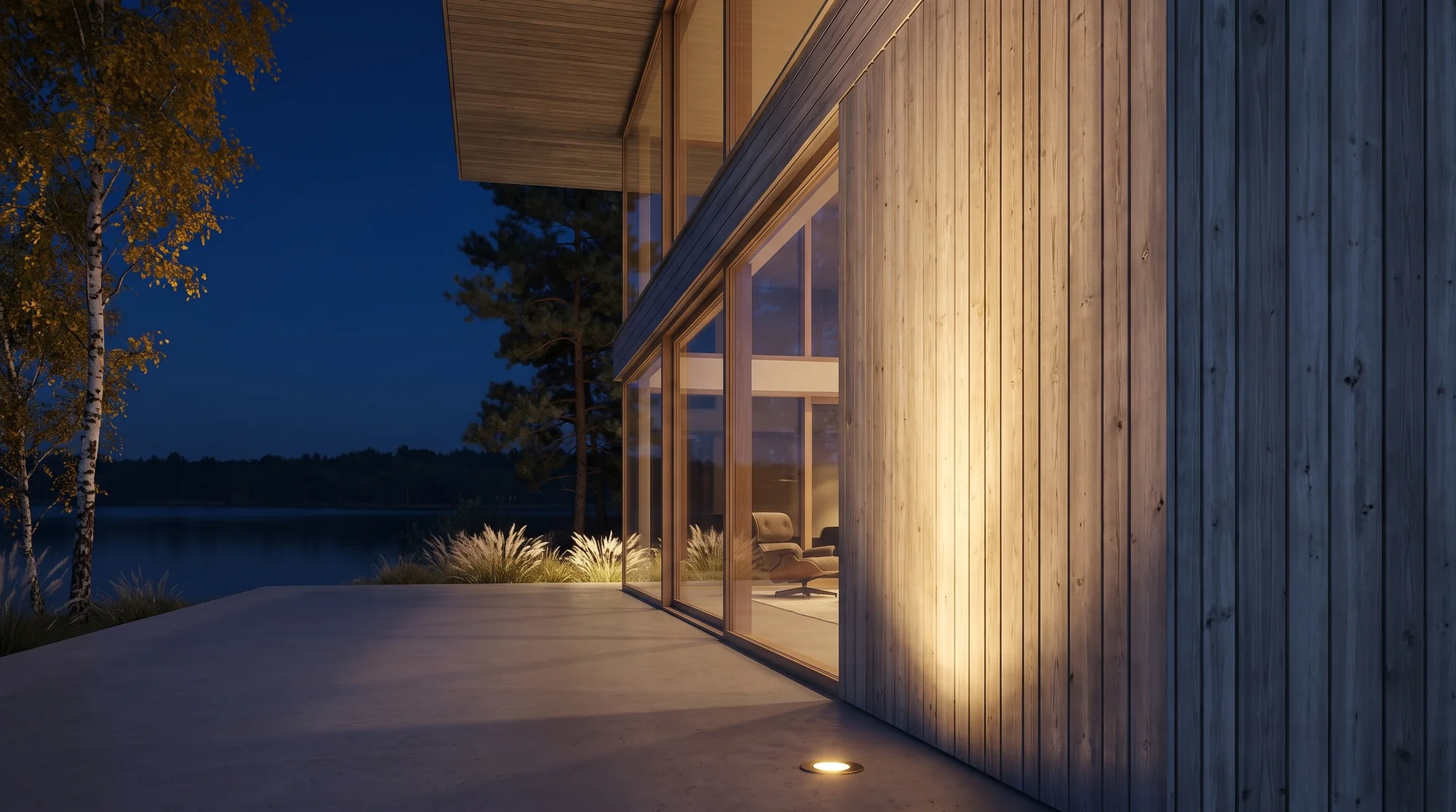 Dusk detail — uplit timber cladding, terrace and lounge chair inside