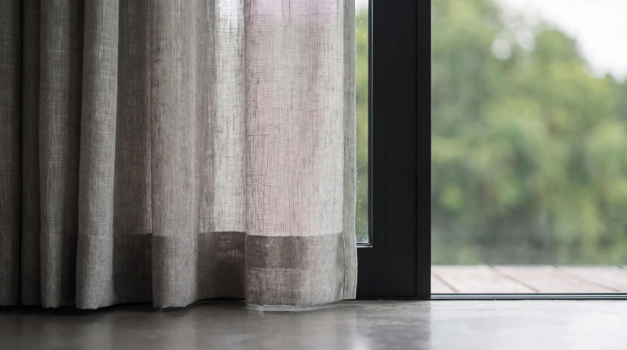 Detail of the linen curtain hem on the polished concrete floor beside the door frame