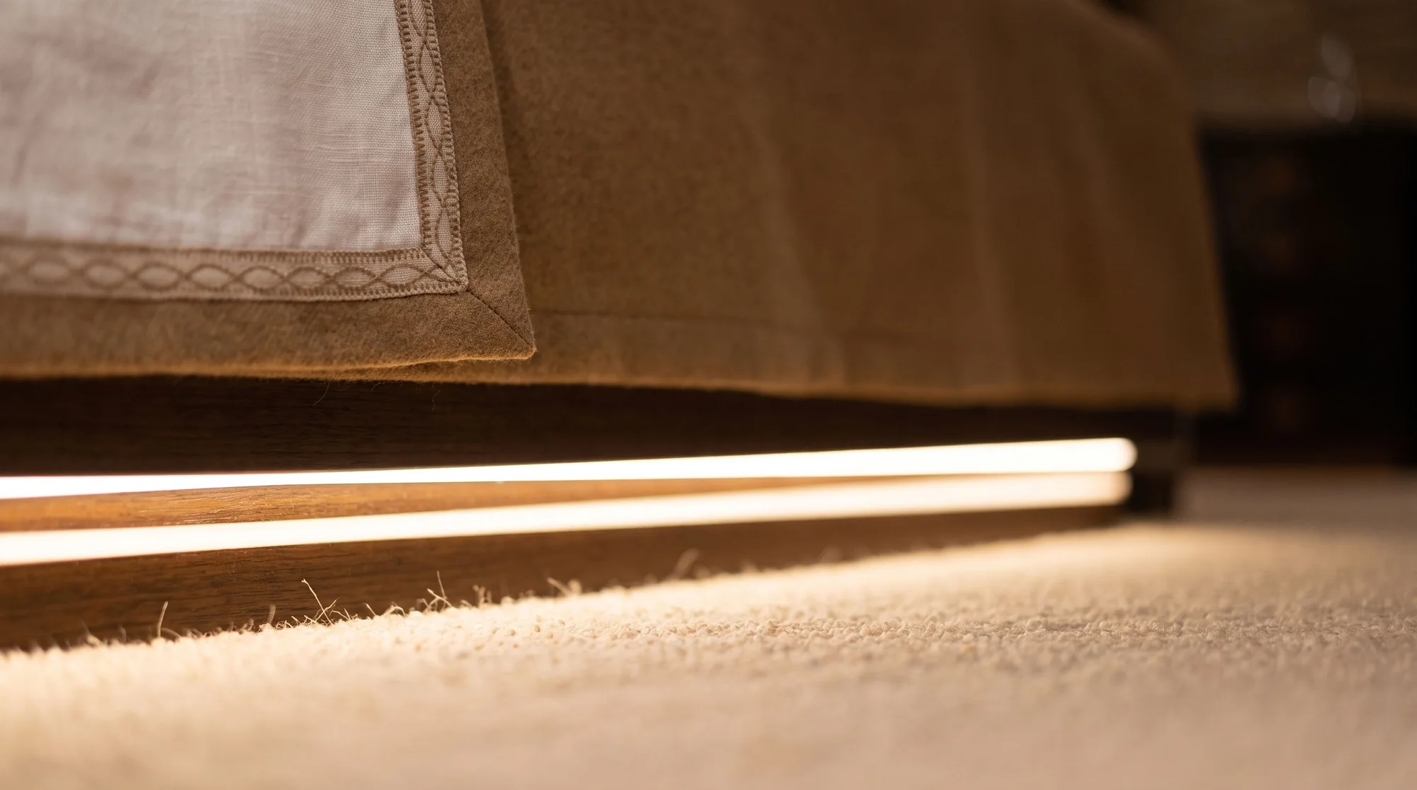 Detail of the bed base with its light edge above the carpet