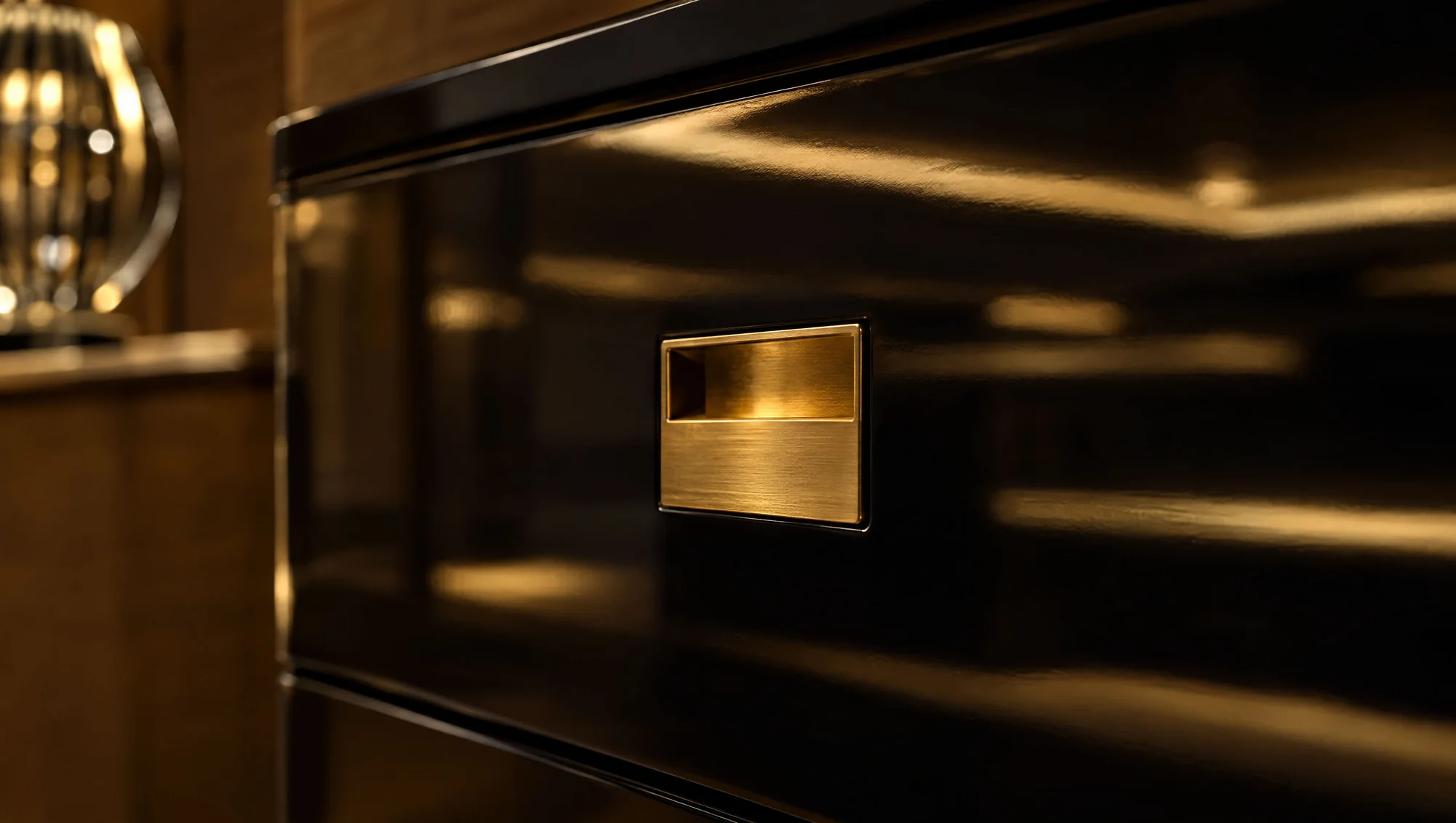 Detail of a brass recessed handle in a black high-gloss dresser