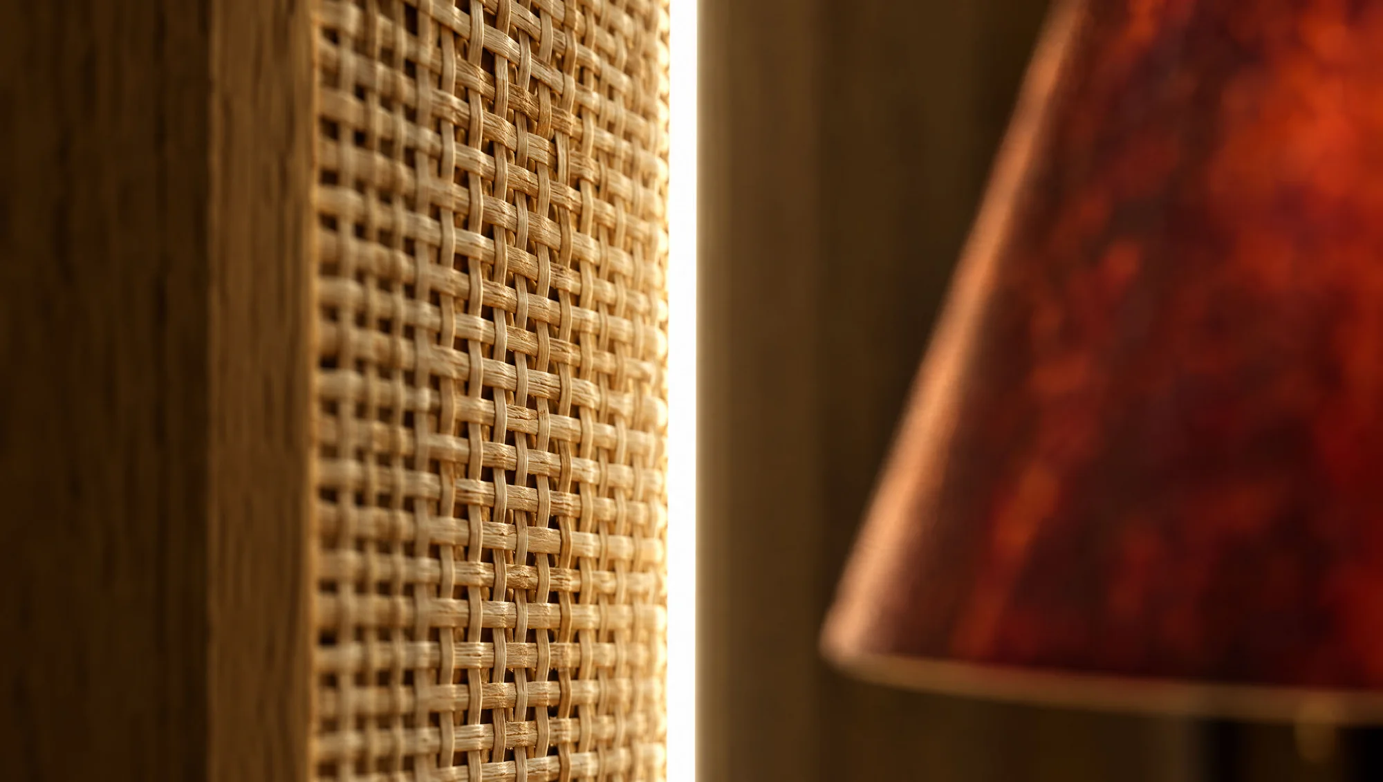 Detail of a backlit woven cane panel beside the red lampshade