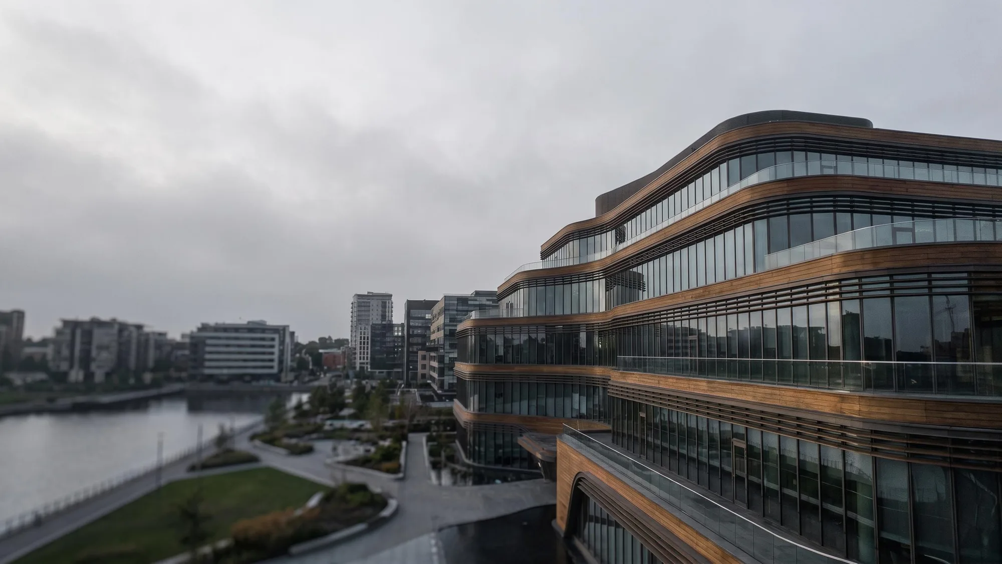 A waterfront office building under a flat, overcast grey sky
