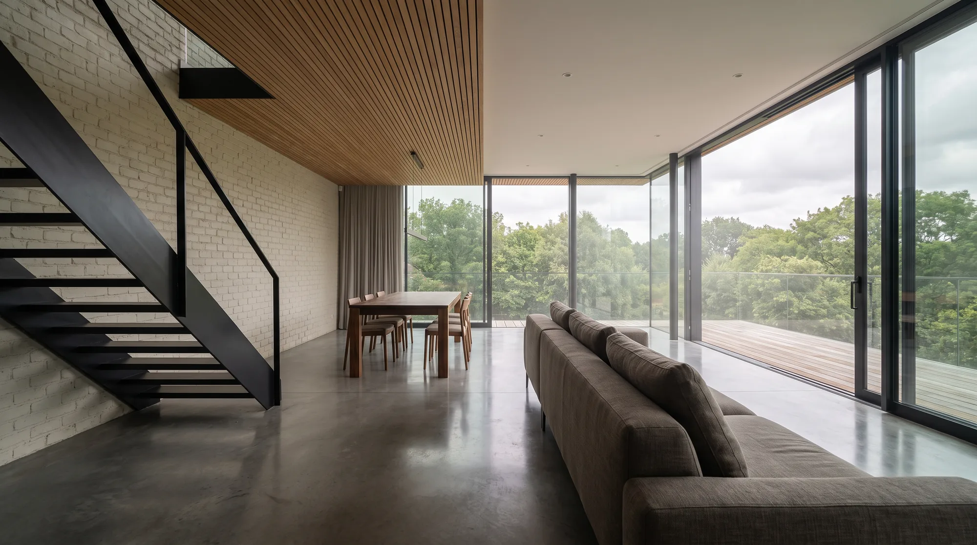 An open-plan living room with concrete floor and full-height glass doors