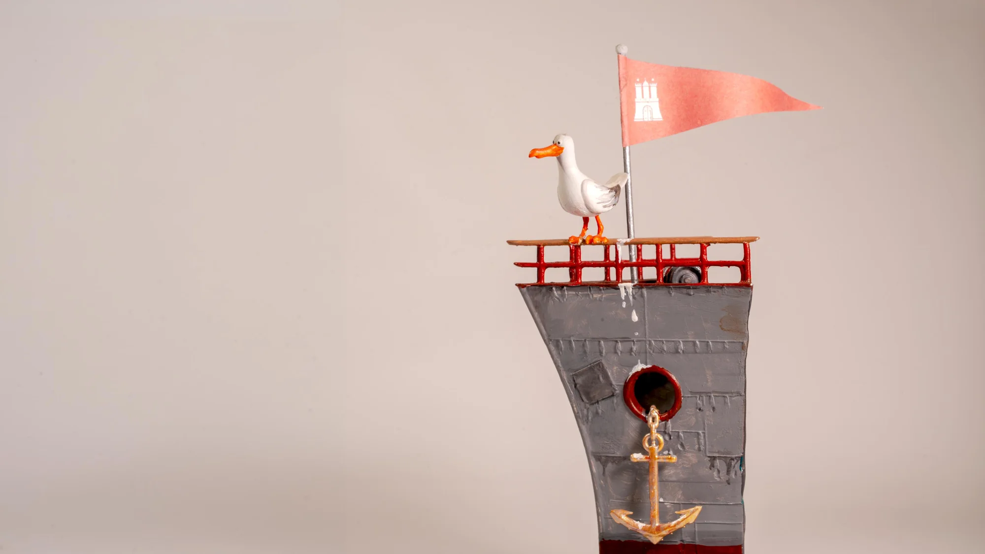 A model seagull with a Hamburg pennant standing on the crow's nest of a toy ship