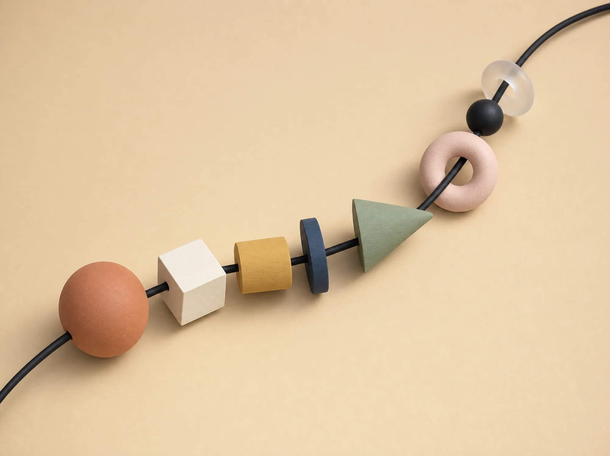 Beads on a black cord — terracotta sphere, cream cube, mustard cylinder, blue disc, sage cone, pink torus, black bead, frosted ring