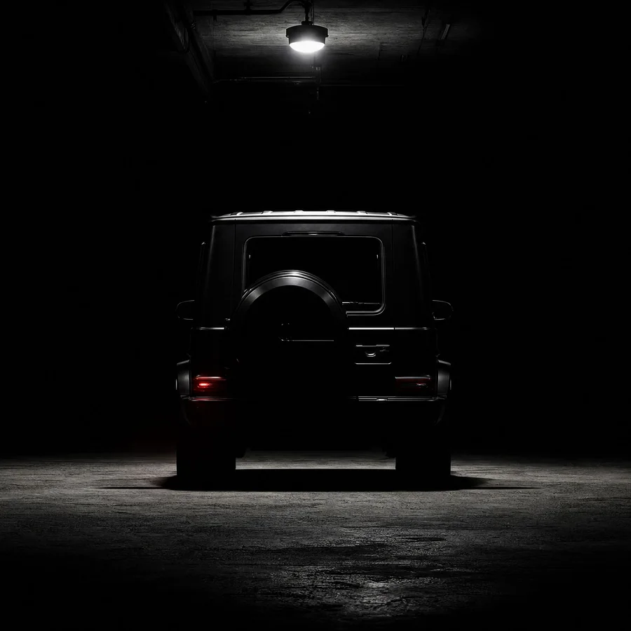 Black Mercedes-Benz G-Class rear view in a dark studio, lit only by a single overhead lamp